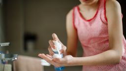 Teenage girl putting facial cleanser in her hands