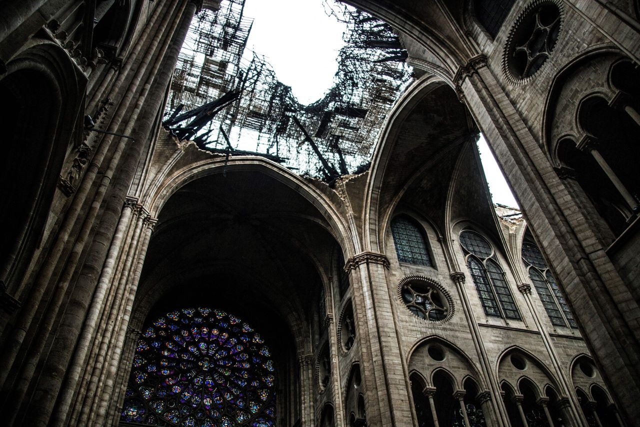 One of the cathedral's famed rose windows appears below the damaged roof of Notre Dame, a day after the blaze broke out on April 16, 2019.