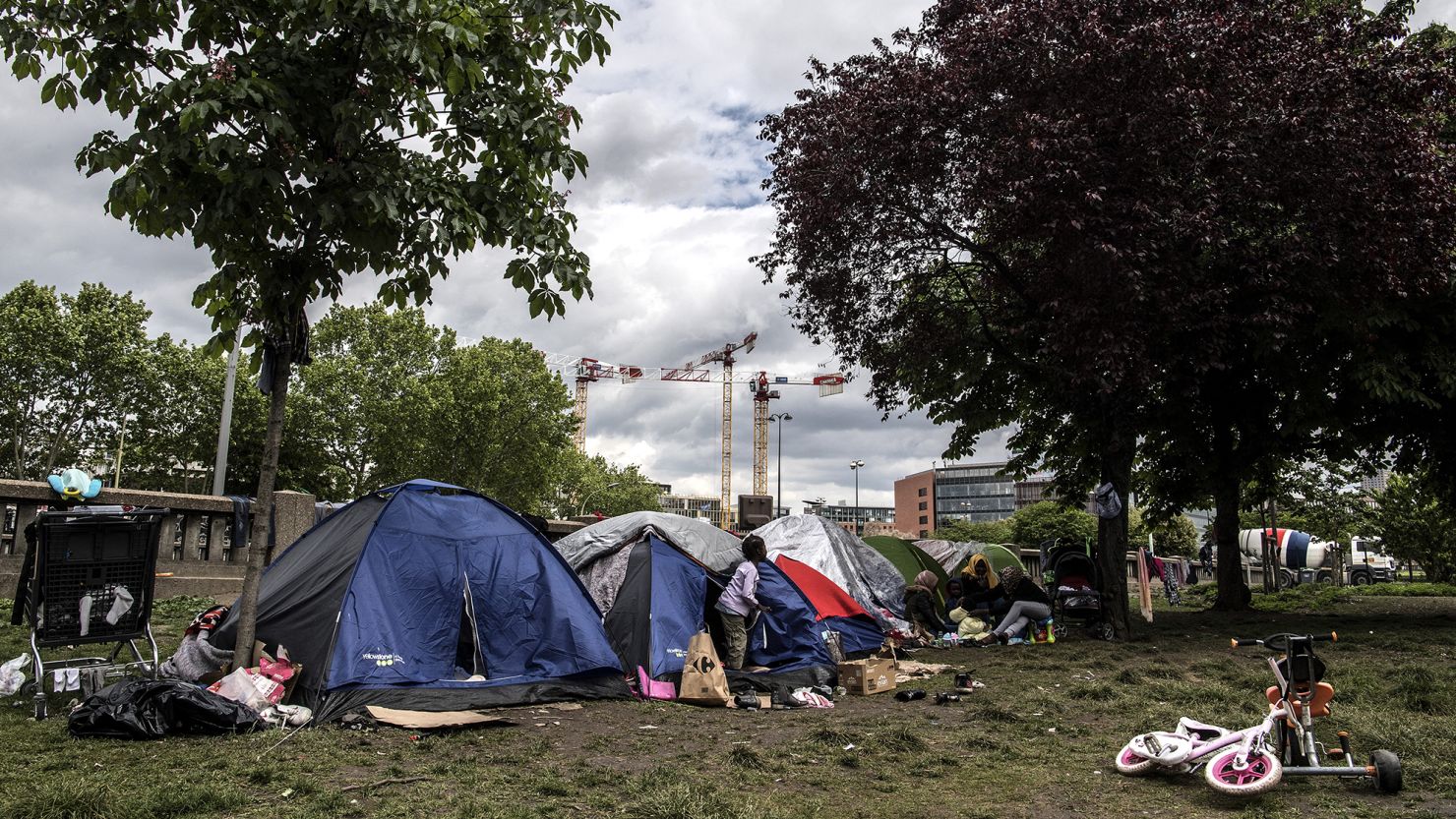 A child walks out of a tent at a makeshift migrant camp set up along Paris's ring road at Porte d'Aubervilliers in Paris on May 10, 2019.
