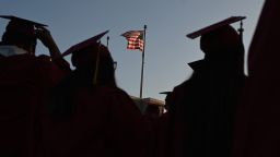 A US flag flies above a building as students earning degrees at Pasadena City College participate in the graduation ceremony, June 14, 2019, in Pasadena, California. - With 45 million borrowers owing $1.5 trillion, the student debt crisis in the United States has exploded in recent years and has become a key electoral issue in the run-up to the 2020 presidential elections. "Somebody who graduates from a public university this year is expected to have over $35,000 in student loan debt on average," said Cody Hounanian, program director of Student Debt Crisis, a California NGO that assists students and is fighting for reforms.