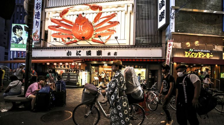 People walk on street in Osaka's Dotonbori region in Japan on June 29, 2019. Osaka's most dynamic region Dotonbori with its neon illuminated signs, various foods, shopping passages, is known as the city's heart and one of tourist area of Osaka. Japanese people also prefer Dotonbori to blow off steam.