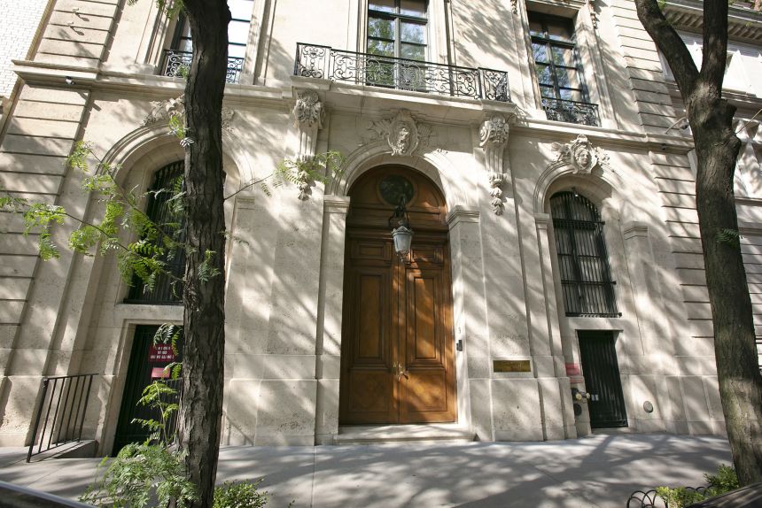 People walk by the Upper East Side New York estate of mulitmillionaire Jeffrey Epstein pm July 9, 2019. Damage on the front doors of the residence was caused by agents serving a search warrant following Epstein's arrest at a nearby New Jersey airport on July 6, 2019.