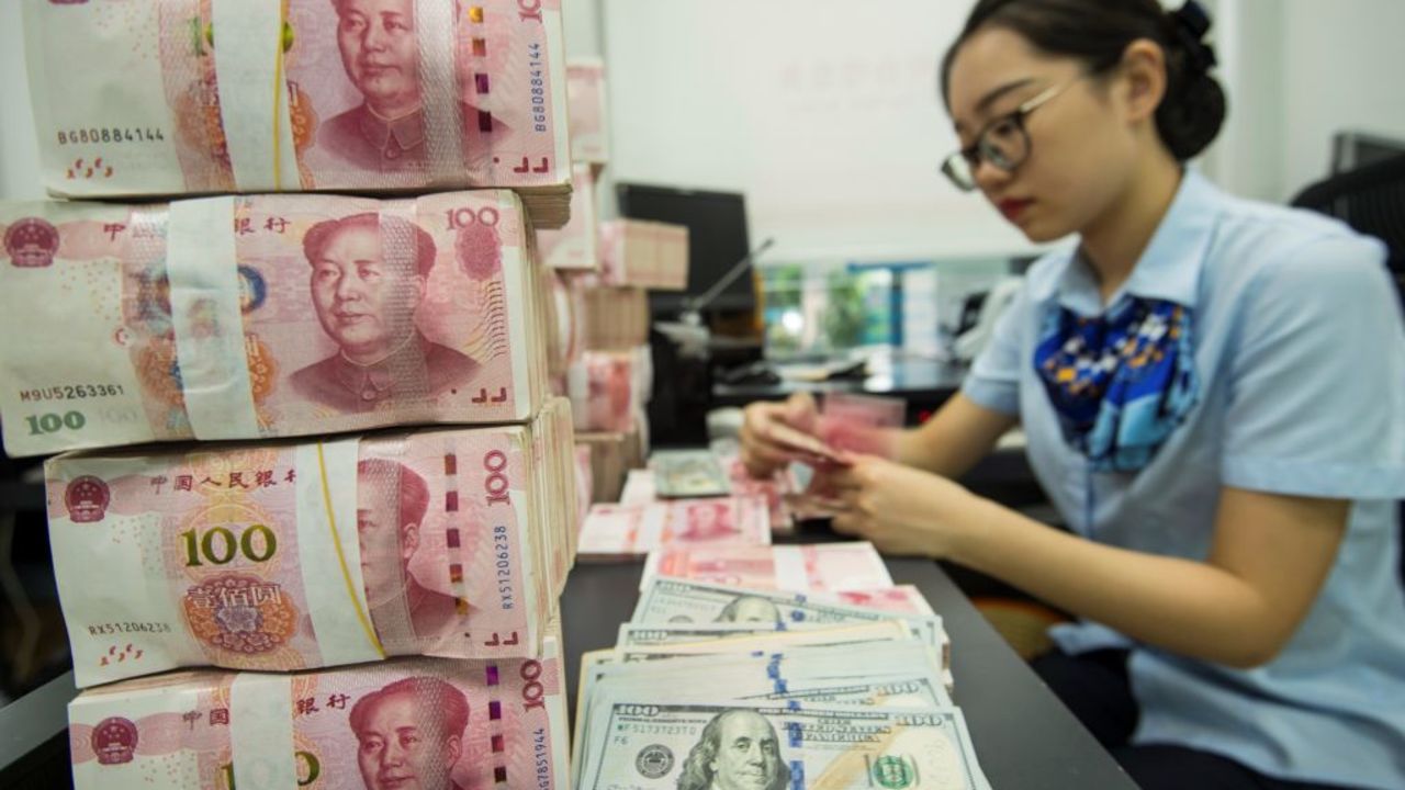 A Chinese bank employee counts 100-yuan notes and US dollar bills at a bank counter in Nantong in China's eastern Jiangsu province on August 28, 2019. - China's currency slid on August 26 to its weakest point in more than 11 years as concerns over the US trade war and the potential for global recession weighed on markets. (Photo by STR / AFP) / China OUT        (Photo credit should read STR/AFP via Getty Images)