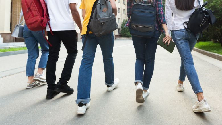 Unrecognizable teenage students in high school campus walking at break, crop