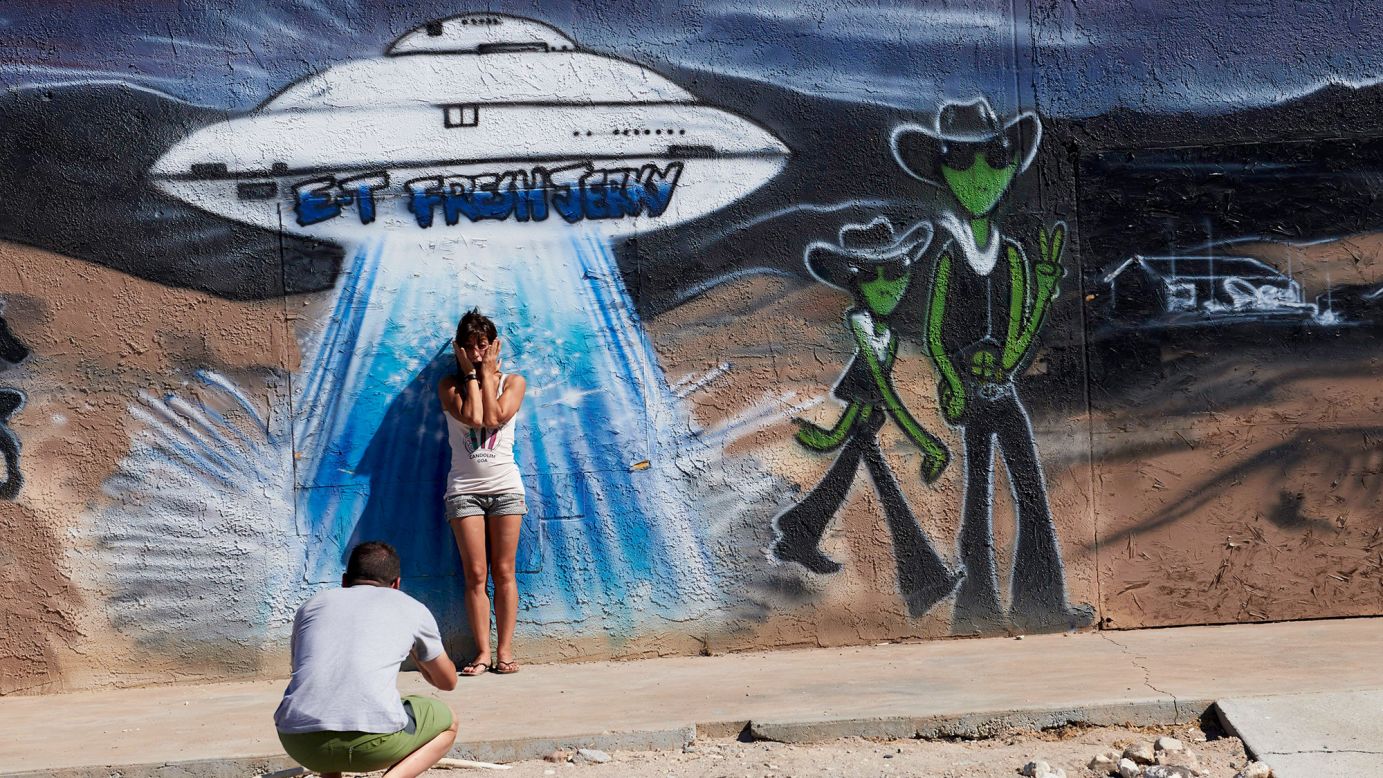 Visitors to the Extraterrestrial Highway take photos in front of a mural depicting aliens and a spaceship outside roadside market E.T. Fresh Jerky.