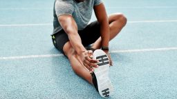 Cropped shot of an unrecognizable athlete sitting alone and stretching before a run on the track