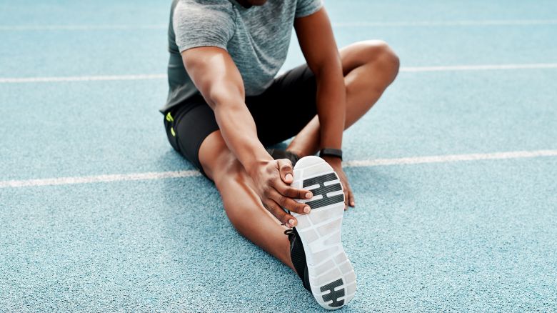 Cropped shot of an unrecognizable athlete sitting alone and stretching before a run on the track