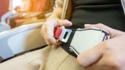 A passenger fastening seat belt while sitting on airplane.
