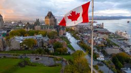 A flowing Canadian flag on a flagpole. Taken at sunset with Old Quebec City and the St. Lawrence River in the background. Aerial HDR view.