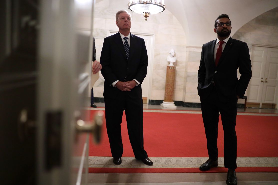 US Sen. Lindsey Graham and Kash Patel listen as President Donald Trump makes a statement in the Diplomatic Reception Room of the White House in October 2019.