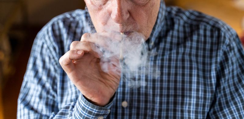 Senior man at home smoking marijuana joint