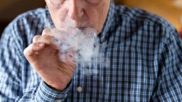 Senior man smoking a marijuana joint at home