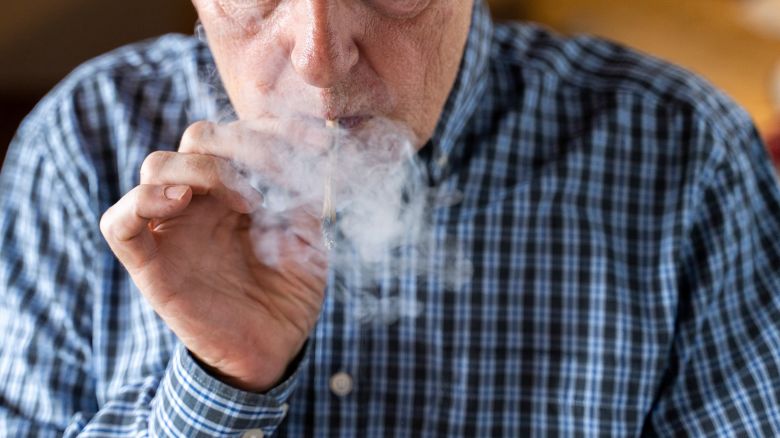 Senior man at home smoking marijuana joint