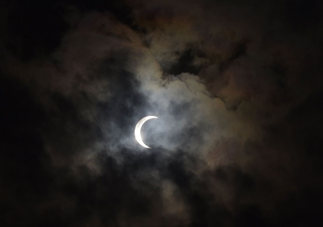 A broken layer of clouds passes below a solar eclipse in Mumbai, India, on December 26, 2019.