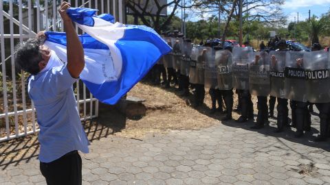 A man flutters a Nicaraguan flag in front of a line of riot police outside the Cathedral after a mass "for Freedom, Justice and Memory" with the presence of of the organization Mothers of April (AMA) in Managua on February 23, 2020. - The AMA is an organization of mothers of youngsters killed during the April 2018 opposition protests. (Photo by INTI OCON / AFP) (Photo by INTI OCON/AFP via Getty Images)