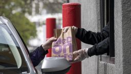 An employee wearing protective gloves hands an order to a customer through a drive-thru window at a McDonald's Corp. restaurant in Oakland, California, U.S., on Thursday, April 9, 2020.