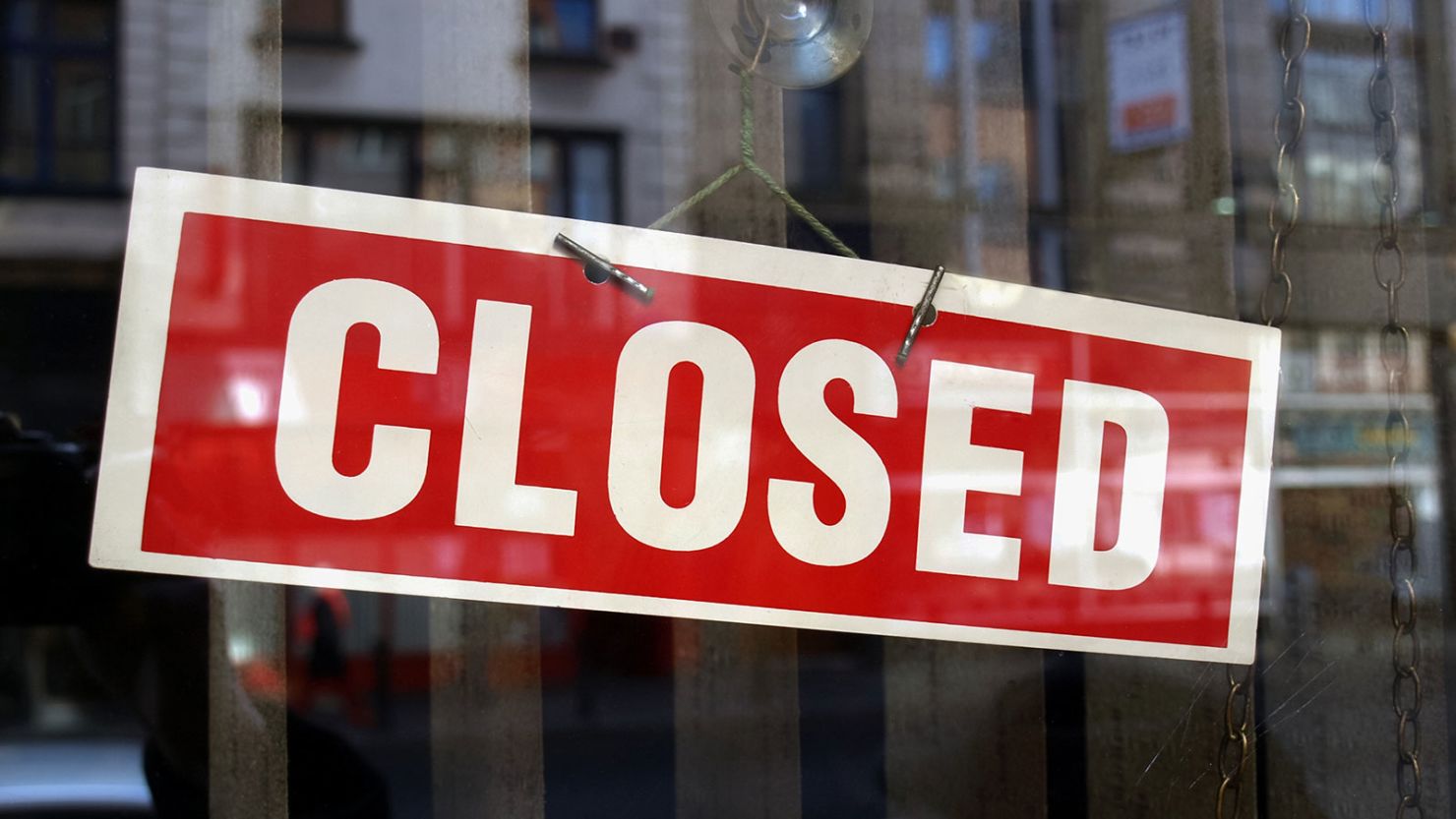 Closed sign a in shop window with blurred background reflections