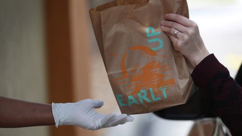 A Taco Bell employee delivers an order to a customer at the drive-up window of the restaurant on March 31, 2020 in Hollywood, Florida.