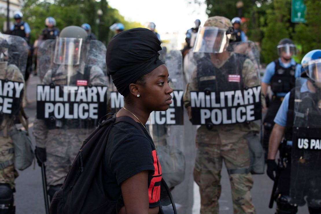 A demonstrator walks in front of a row of military police members wearing riot gear as they push back demonstrators outside of the White House, June 1, 2020 in Washington D.C., during a protest over the death of George Floyd.