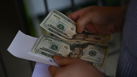 A woman counts money outside a U.S. remittance collection agency in San Isidro, 70 km northeast of San Salvador, on June 10, 2020, amid the new coronavirus pandemic. - The drop of remittances, which represents the 16% of the gross domestic product (GDP) of El Salvador, is attributed to the loss of jobs in the US due to the COVID-19 pandemic. GUatemala and Honduras have also seen their incomes reduced. (Photo by MARVIN RECINOS / AFP) (Photo by MARVIN RECINOS/AFP via Getty Images)