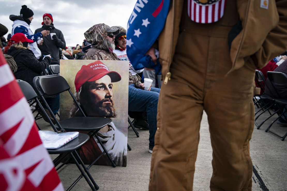 An attendee walks past a poster of Jesus wearing a "Make America Great Again" hat at a campaign rally for then-President Donald Trump in Avoca, Pennsylvania, on November 2, 2020.