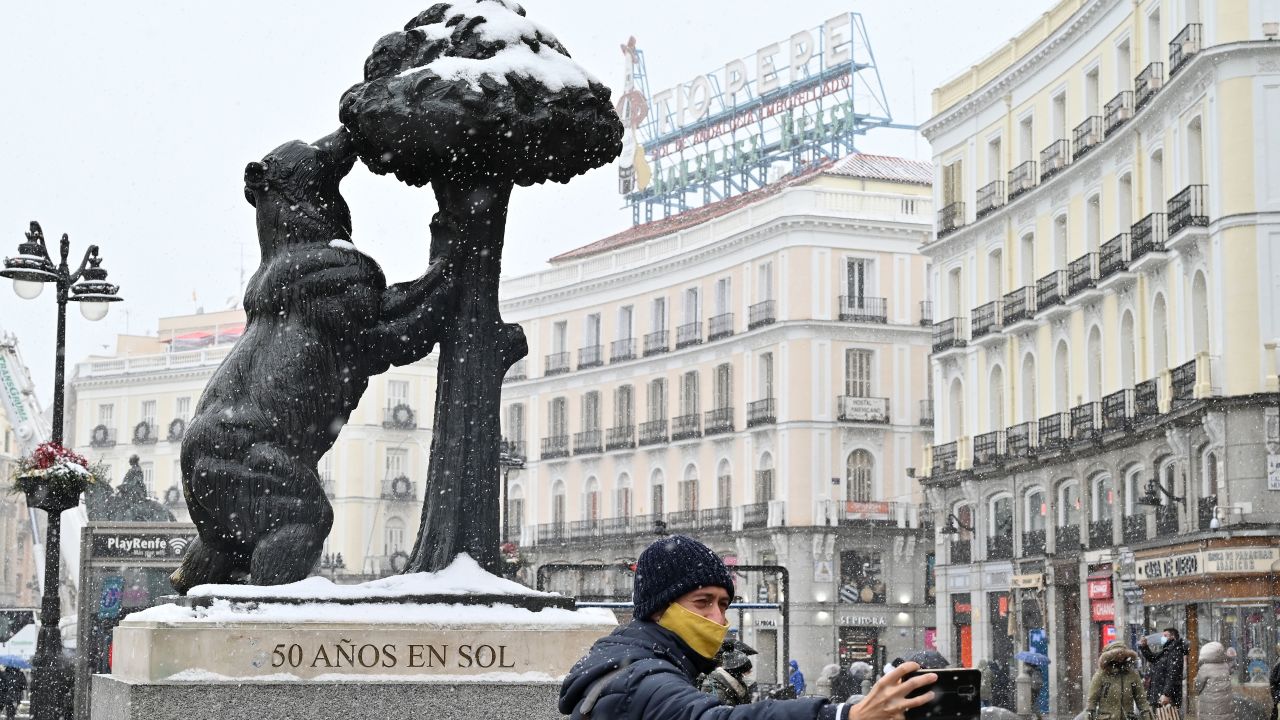 A man takes a selfie picture next to the "El Oso y El Madrono" (the bear and the strawberry tree) statue in Puerta del Sol square in Madrid on January 8, 2021 during a snow fall. - Heavy snow was falling due to Filomena storm in Madrid and across parts of Spain today which could cover up to half of the country, causing a big drop in temperatures. (Photo by GABRIEL BOUYS / AFP) (Photo by GABRIEL BOUYS/AFP via Getty Images)