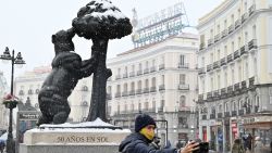 A man takes a selfie picture next to the "El Oso y El Madrono" (the bear and the strawberry tree) statue in Puerta del Sol square in Madrid on January 8, 2021 during a snow fall. - Heavy snow was falling due to Filomena storm in Madrid and across parts of Spain today which could cover up to half of the country, causing a big drop in temperatures. (Photo by GABRIEL BOUYS / AFP) (Photo by GABRIEL BOUYS/AFP via Getty Images)