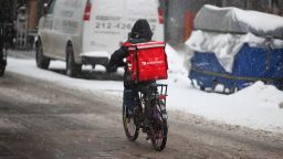 A food delivery worker on a bicycle is seen as snowfall blankets Times Square in New York City in December 2021.