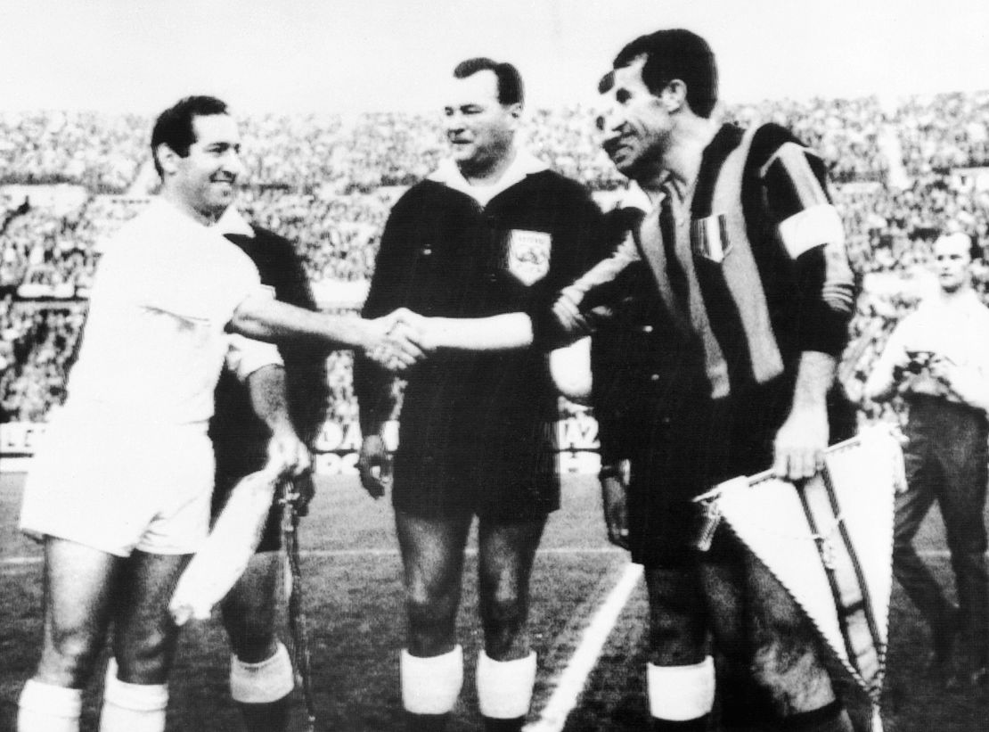 Francisco Gento (i), capitán del Real Madrid, y Armando Picchi (d), capitán del Inter de Milán, se dan la mano e intercambian banderines antes del partido de la final de la Copa de Europa de Clubes. 28 de mayo de 1964.