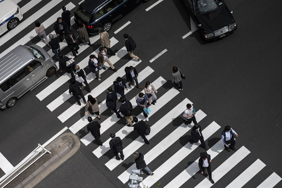 Pedestrians including office employees cross a street in Tokyo's Shimbashi area at lunchtime on April 1, 2021.