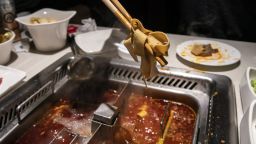 A customer ladles some tofu out of a hotpot at a Haidilao restaurant in Shanghai.