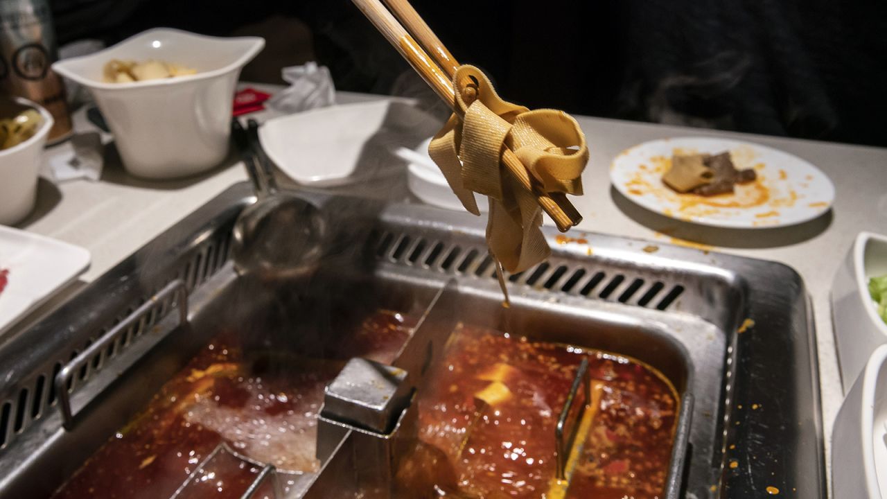 A customer ladles some tofu out of a hotpot at a Haidilao restaurant in Shanghai.