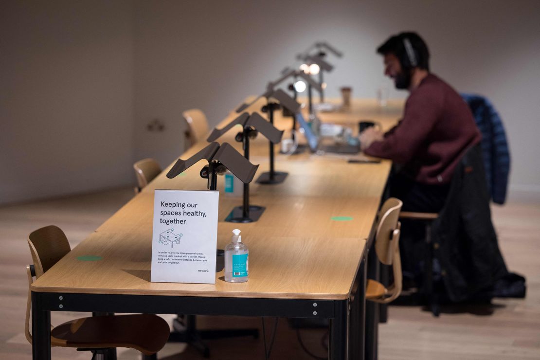 A person works at a shared workspace near signage advising people to maintain social distance at the WeWork, coworking and office space in the City of London, on April 13, 2021, as the company enhances health and safety standards in response to COVID-19.