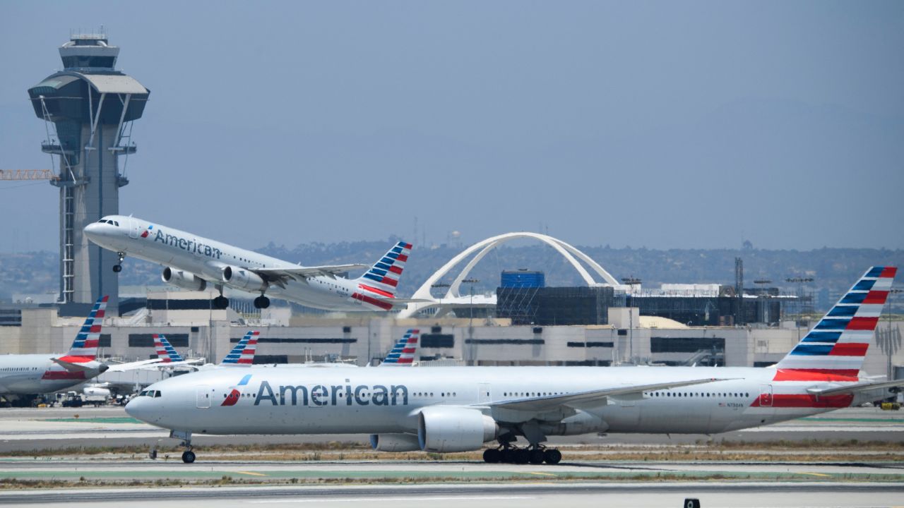 An American Airlines, Inc. Airbus SE A321 aircraft takes off as a Boeing Co. 777-300ER taxis on the tarmac at Los Angeles International Airport (LAX) on July 6, 2021 in Los Angeles, California. - The LAX airport celebrates 60 years since the opening of the "Jet Age" terminals and Theme Building as a $14.5 billion airport infrastructure modernization and transit construction project continues ahead of the 2028 Los Angeles Olympics.