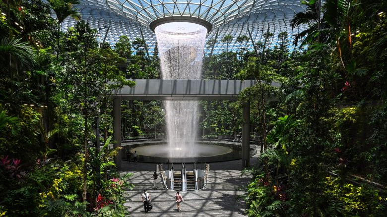 People walk past the Rain Vortex indoor waterfall feature at Jewel Changi Airport in Singapore on August 19, 2021. (Photo by Roslan RAHMAN / AFP) (Photo by ROSLAN RAHMAN/AFP via Getty Images)