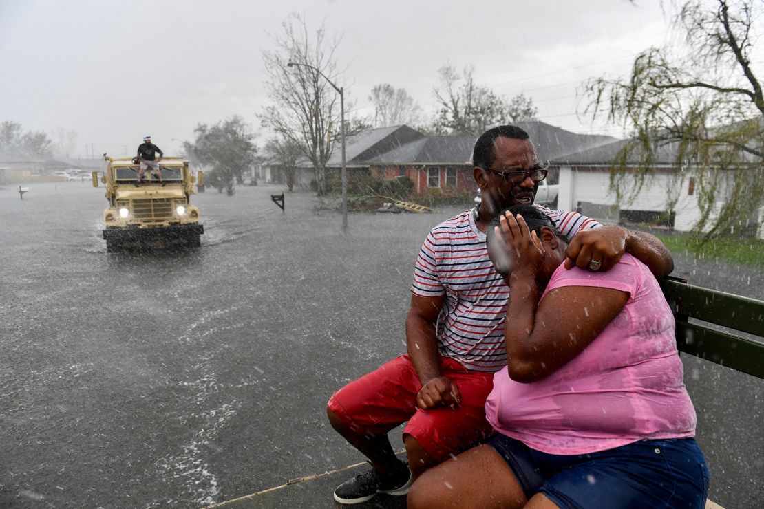 People are soaked by rain from Hurricane Ida while evacuating out of a flooded neighborhood in a high water truck after neighborhoods flooded in LaPlace, Louisiana, on August 30, 2021.