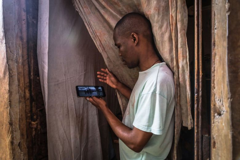 A young man in Kenya streaming a movie on Netflix using an android smartphone.