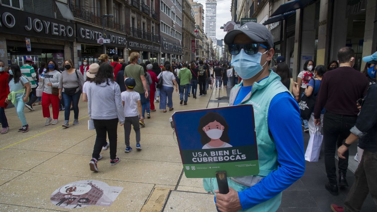 An employee of the Secretary of Government holds a sign reading "Use the face mask properly" in the historic centre of Mexico City on October 16, 2021 a day after the Mexican capital mayor's office announced it will reduce the restrictions put in place to fight the novel coronavirus to COVID-19 as of next Monday - As COVID-19 infections and hospitalizations decrease, the health alert in the capital will go from yellow to green, which allows bars, nightclubs and discos to extended their service time by one hour, Eduardo Clark, director of technology of the government, said at a press conference. Meanwhile, restrictions on the capacity of massive outdoor events such as football matches and cultural events, which stood at 75%, will be eliminated. (Photo by Claudio CRUZ / AFP) (Photo by CLAUDIO CRUZ/AFP via Getty Images)