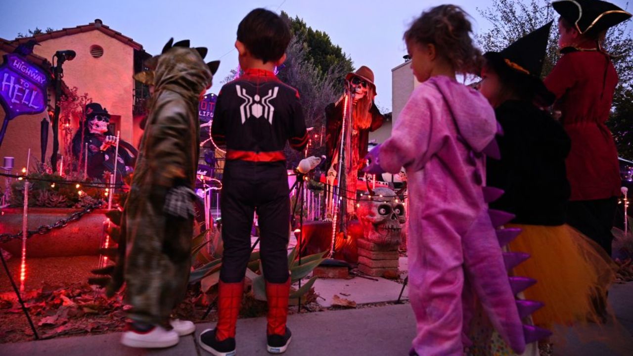 Children dressed in costumes look at a home decorated for Halloween, in Burbank, California, October 30, 2021. - Last year's Halloween celebrations were severely curtailed due to the Covid-19 pandemic. (Photo by Robyn Beck / AFP) (Photo by ROBYN BECK/AFP via Getty Images)