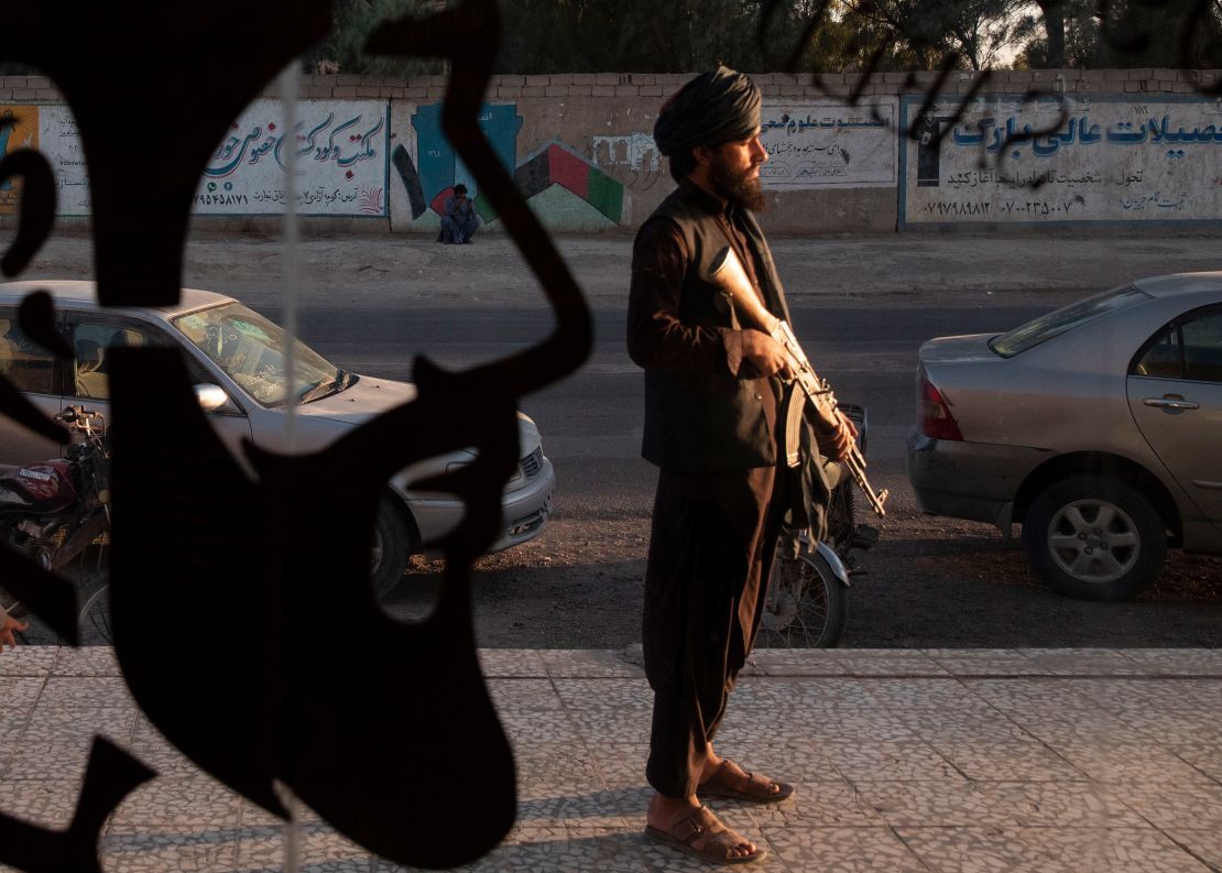 A Taliban fighter stands in front of a men's barber shop in Zaranj, the capital of Afghanistan's Nimroz province, on October 14, 2021.