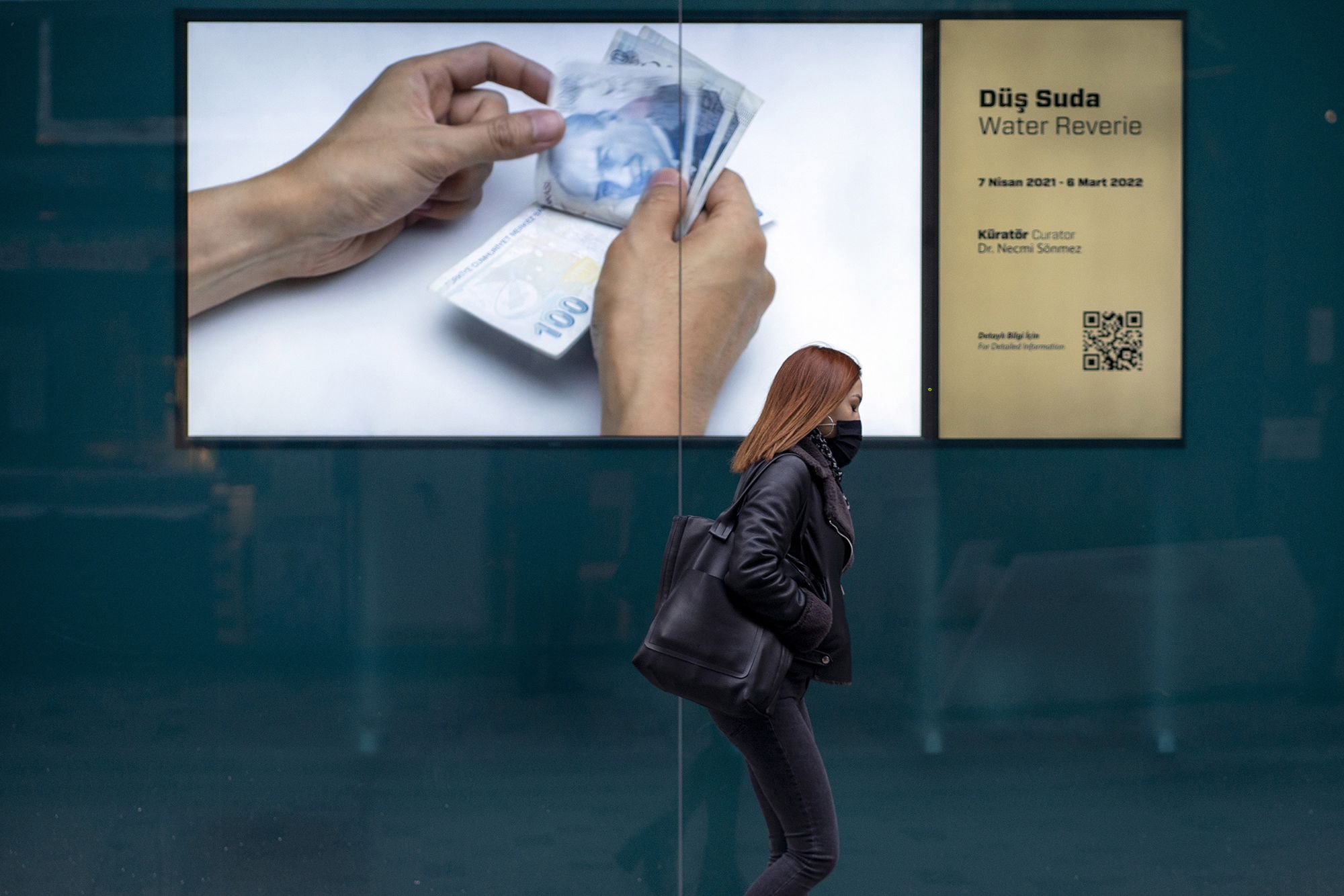 A pedestrian walks by an advertisement showing Turkish lira banknotes on Istiklal Street in Istanbul, Turkey on December 20, 2021.