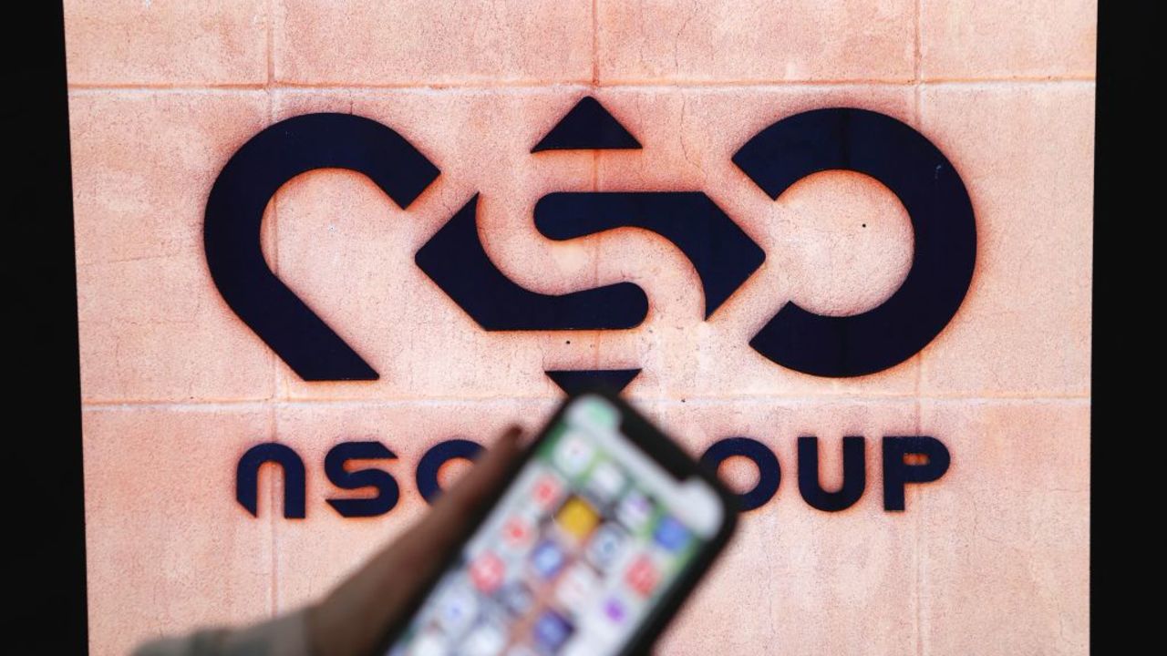 A photographic illustration shows a mobile phone near the NSO Group company logo on February 9, 2022 in the Israeli city of Netanya. - Israel's ground-breaking surveillance technology was once feted as a prized export bolstering diplomatic ties abroad, but reports the secret spyware was also turned on citizens at home has trigged domestic outrage. Recent bombshell allegations in Israeli media centre on the controversial Pegasus malware made by the Israeli firm NSO, which can turn a phone into a pocket spying device. (Photo by JACK GUEZ / AFP) (Photo by JACK GUEZ/AFP via Getty Images)