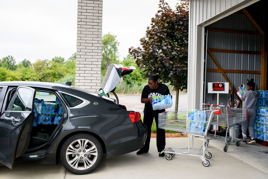 Diana Wiley Washington, 58, works with her daughter in August 2021 to load bottled water in their car for delivery to local seniors as part of an outreach program through their church in Flint, Michigan.