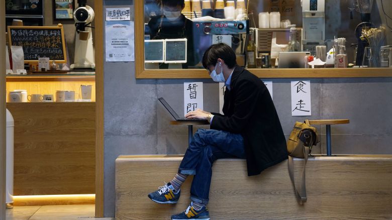 A man uses his laptop outside a coffee shop in Shanghai, China, in March 2022.