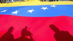 TOPSHOT - Supporters of embattled Venezuelan President Hugo Chavez stand behind the Venezuelan flag while demonstrating in Caracas, 06 January 2003. Supporters of Chavez 06 January angrily protested the deaths of two militants, while the opposition stepped up its defiance as a crippling strike entered a sixth week. Chanting "popular justice," more than 1,000 pro-Chavez activists demonstrated outside the prosecutor general's offices, demanding punishment for the police officers they say killed two fellow "chavistas" during clashes with the opposition 03 January. 

Simpatizantes del presidente Hugo Chávez extienden una bandera venezolana en una concentracióon realizada frente a la sede de la Fiscalia General de la República, en Caracas, el 06 de enero de 2003. Seguidores de Chávez comienzan a concentrarse este lunes a las puertas de la Fiscalía de Caracas, para pedir justicia por dos muertes ocurridas en los últimos enfrentamientos callejeros en este país en tensión al entrar en la sexta semana de paro general. (Photo by Juan BARRETO / AFP) (Photo by JUAN BARRETO/AFP via Getty Images)