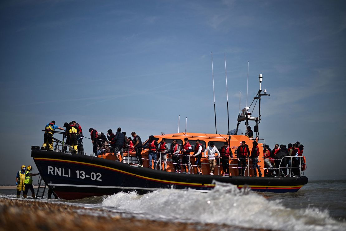 In this June 2022 photo, migrants, picked up at sea attempting to cross the English Channel, are helped ashore from an Royal National Lifeboat Institution's lifeboat at Dungeness on the southeast coast of England.