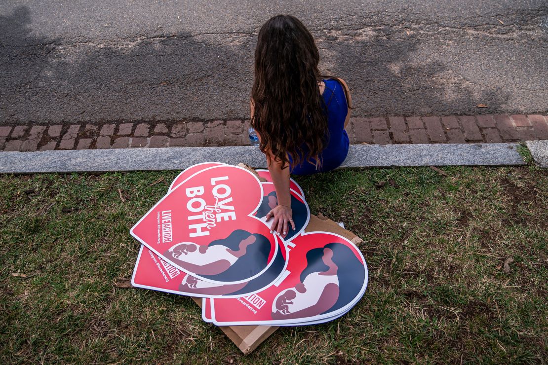 A woman rests next to anti-abortion posters in front of the US Supreme Court on June 24, 2022.