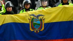 Police officers stand guard behind an Ecuadorean national flag in the surroundings of the National Assembly in Quito on June 25, 2022, when a parliamentary session called by opposition lawmakers for a no confidence vote against President Guillermo Lasso will be held in the framework of indigenous-led protests against the government. - An estimated 14,000 protesters are taking part in a nationwide show of discontent against rising hardship in an economy dealt a serious blow by the coronavirus pandemic. Protesters are demanding a cut in already subsidized fuel prices, which have risen sharply in recent months, as well as jobs, food price controls, and more public spending on healthcare and education. (Photo by Rodrigo BUENDIA / AFP) (Photo by RODRIGO BUENDIA/AFP via Getty Images)