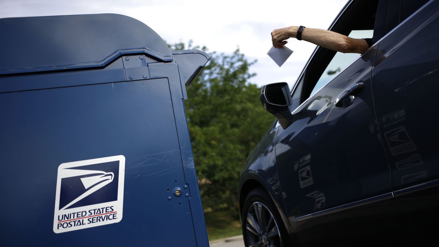A motorist drops a letter into a USPS mail drop box at a post office in Kentucky in 2022.
