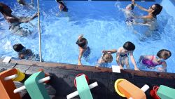 Children take a swimming lesson with lifeguards in a mobile swimming pool made from a shipping containers in Hangenbieten, eastern France,  on July 13, 2022. - The mobile swimming pool travels travels through towns to give swimming lessons to children, aiming to prevent risks of drowning. (Photo by Frederick FLORIN / AFP) (Photo by FREDERICK FLORIN/AFP via Getty Images)